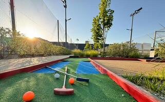 minigolf klubbar och bollar av annorlunda färger lagd på artificiell gräs. foto