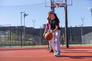 en Lycklig mor och barn dotter utanför på basketboll domstol. foto