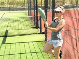 kvinna spelare tjänande boll. ung vuxen flicka spela tennis utanför arena. person racket slå spel klubb. människor grupp träffa sport domstol match. passa vård fri tid. springa skicklighet tåg. padel tennis team träna foto