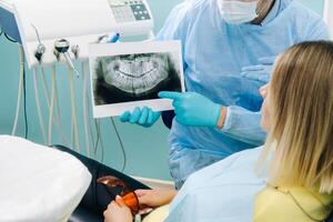 tandläkare förklara de detaljer av de röntgen till hans patient i de kontor foto