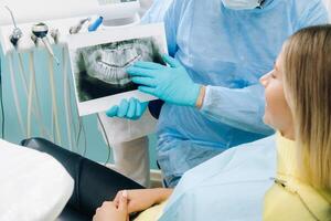tandläkare förklara de detaljer av de röntgen till hans patient i de kontor foto