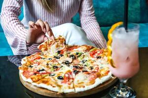 kvinna Sammanträde på tabell med pizza och dryck foto