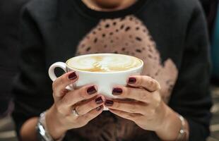 kvinna innehav en kaffe kopp i henne händer foto