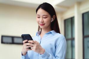 en företag kvinna är använder sig av de smart telefon medan stående utanför foto