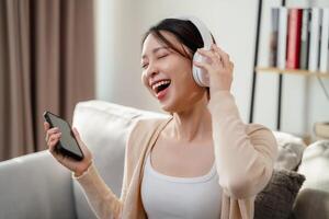 en kvinna är leende och sång in i en cell telefon foto