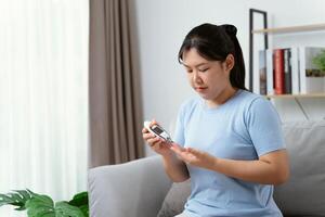 asiatisk kvinna kontroll blod socker nivå förbi digital glukos meter foto