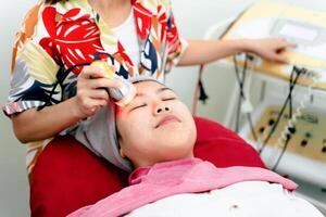 kosmetologer prestera ultraljud ansiktsbehandling förfaranden med Utrustning. kvinna få ansiktsbehandling massage. foto