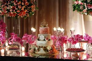 sofistikerad rosa tema fest med blommor, sötsaker, ljus och blommor och krönt kaka foto