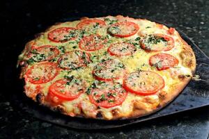 margherita pizza kommande ut av de ugn med ost, tomat sås och basilika foto