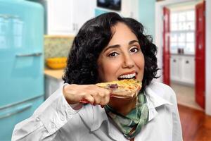 leende brunett modell med henne bit av pizza foto