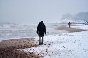 ledsen man gående längs hav i vinter. depression, upplösning foto