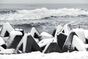 betong vågbrytare täckt med snö, vinter havet bakgrund foto