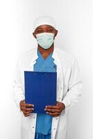 svart kirurg läkare man i vit täcka keps och kirurg mask innehar medicinsk uppgifter med diagnos foto