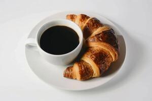 svart kaffe och croissant på vit bakgrund foto