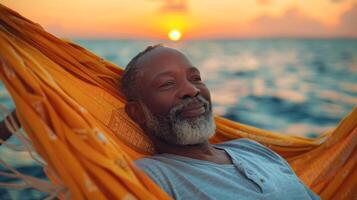 mogna afrikansk amerikan man åtnjuter avkopplande i en hängmatta, på hav solnedgång bakgrund. perfekt för främja avslappning, resa, semester destinationer, och lugn stunder foto