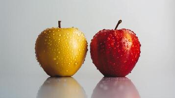 två äpplen, ett gul och ett röd, täckt i vatten droppar på en reflekterande yta. foto