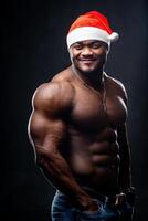 atletisk muskulös man utan skjorta med en santa hatt. Semester av jul med sportig manlig modell. foto