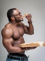 afrikansk man äter utsökt pizza. stark attraktiv man med pizza. foto