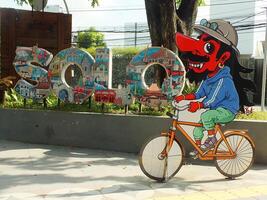 surakarta, april 11 2024, stad promenad med de ord solo- och en wayang maskot runt manahan stadion. ikoniska landmärke wayang karaktär ridning en cykel. foto