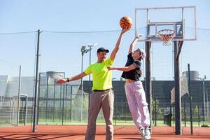 en Lycklig far och tonåring dotter spelar basketboll utanför på domstol. foto