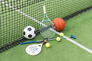 en mängd av sporter Utrustning Inklusive ett amerikan fotboll, en fotboll boll, en tennis racket, en tennis boll, och en basketboll foto