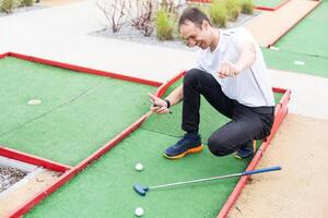 spelare utseende på hans träffa på en mini golf kurs foto