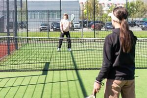 positiv mor och dotter stående på domstol med padel racketar foto