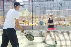 ukraina Kiev, april 02 2024. Lycklig atletisk par har roligt medan spelar padel tennis dubbel match på utomhus- domstol. foto