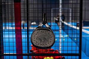 svart professionell paddla tennis racket och boll med naturlig belysning på blå bakgrund. horisontell sport tema affisch, hälsning kort, rubriker, hemsida och app foto