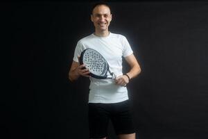 padel tennis spelare med racket i händer. paddla tennis, på en svart bakgrund. foto