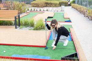 kvinna spelar mini golf på kurs. sommar sport och fritid aktivitet foto