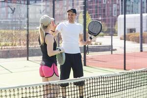 ung kvinna spelar padel tennis med partner i de öppen luft tennis domstol foto