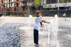 Lycklig unge spelar i en fontän med vatten foto