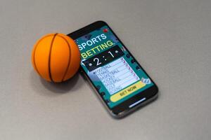 smartphone med Ansökan för sport satsningar och en basketboll boll, begrepp av uppkopplad satsningar foto