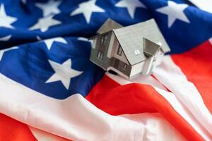 hus modell nära USA flagga. verklig egendom försäljning och inköp begrepp. Plats för text. foto