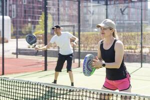 ukraina Kiev, april 02 2024. Lycklig atletisk par har roligt medan spelar padel tennis dubbel match på utomhus- domstol. foto