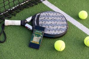 hög vinkel se av mobil telefon med tennis Utrustning på domstol bakgrund foto