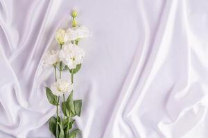 delikat bröllop bakgrund för design, kort, inbjudan. vit veck av de satin tyg och vit färsk blommor. romantisk design. en kopia Plats foto