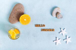 begrepp Hej sommar text, cocktail, orange, stenar och sjöstjärna på blå topp se foto