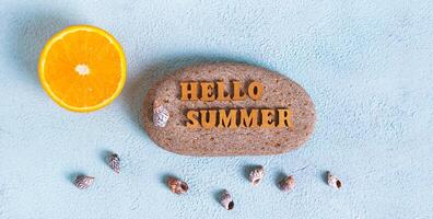 begrepp Hej sommar text på sten, halv orange och snäckskal på blå bakgrund topp se webb baner foto