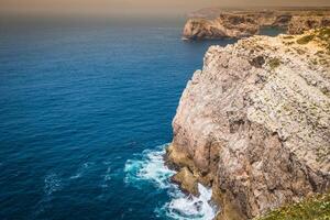 hög klippor och blå hav på cabo sao vicente på kust av portugal foto
