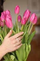 närbild av de detaljer av de flickans förskönad händer med Smycken innehav rosa blommor. foto