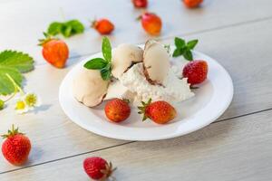 färsk organisk stuga ost med jordgubbar och is grädde i en tallrik på en trä- tabell foto