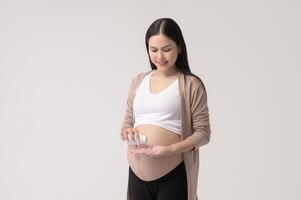 porträtt av skön gravid kvinna tar piller och vitamin över vit bakgrund studio, hälsa och moderskap begrepp foto