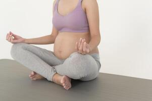 friska gravid kvinna utövar och håller på med prenatal yoga, meditation, arbetssätt ut, yoga, graviditet begrepp. foto