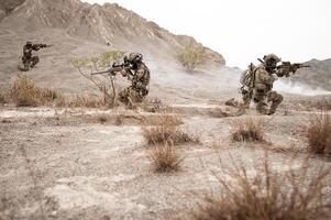 soldater i kamouflage uniformer siktar med deras gevär redo till brand under militär drift i de öken- , soldater Träning i en militär drift foto