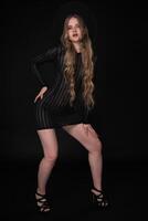 full längd porträtt av en ung kvinna, 21 år gammal, med lång ben, Framställ mot svart bakgrund foto