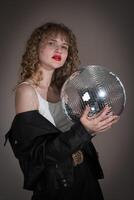 porträtt av kvinna innehav spegel disko boll, ser på kamera under firande fest i nattklubb foto