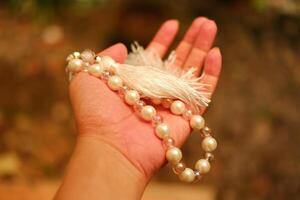 pärla halsband i de hand av en ung kvinna, närbild av Foto