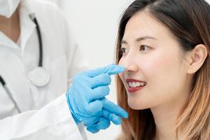 plast kirurgi, skönhet, kirurg eller kosmetolog rörande kvinna ansikte, kirurgisk procedur den där engagera förändras form av näsa, läkare undersöker patient näsa innan näsplastik, medicinsk bistånd, hälsa foto